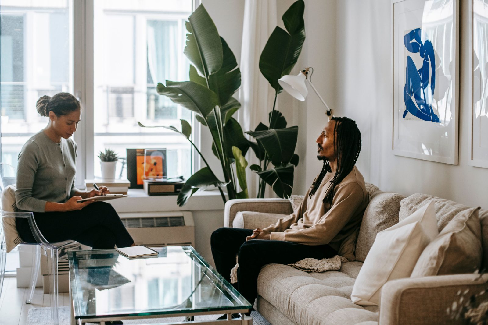 A black man in conversation with his therapist in a calm, sunlit living room